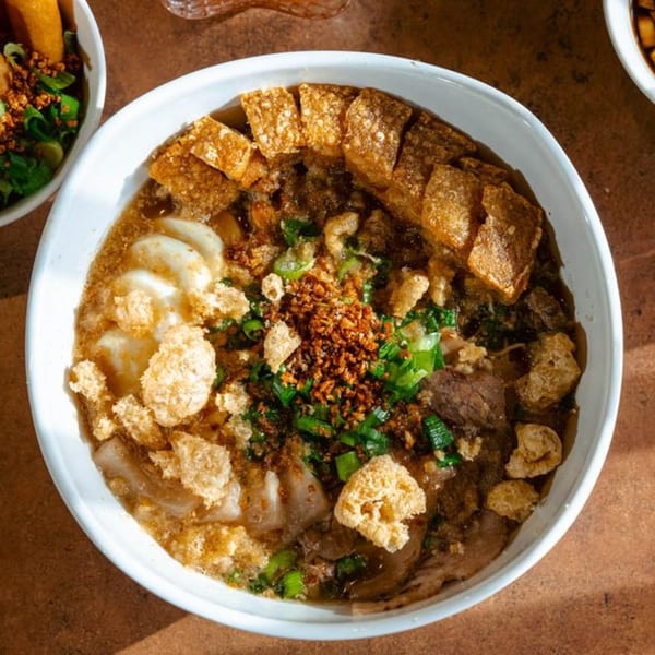 Overhead view of a Filipino mami noodle soup with chicharon, meat, and green onions.