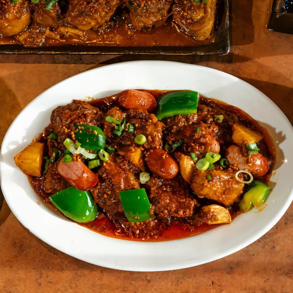 Filipino menudo with pork, liver, hot dogs, potatoes, and bell peppers in a rich sauce.