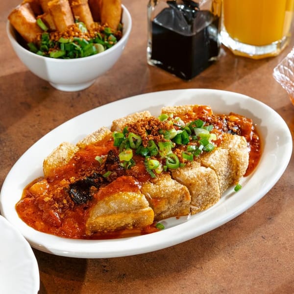 Crispy fried pork belly, lechon kawali, with a rich red sauce, green onions, and fried garlic.